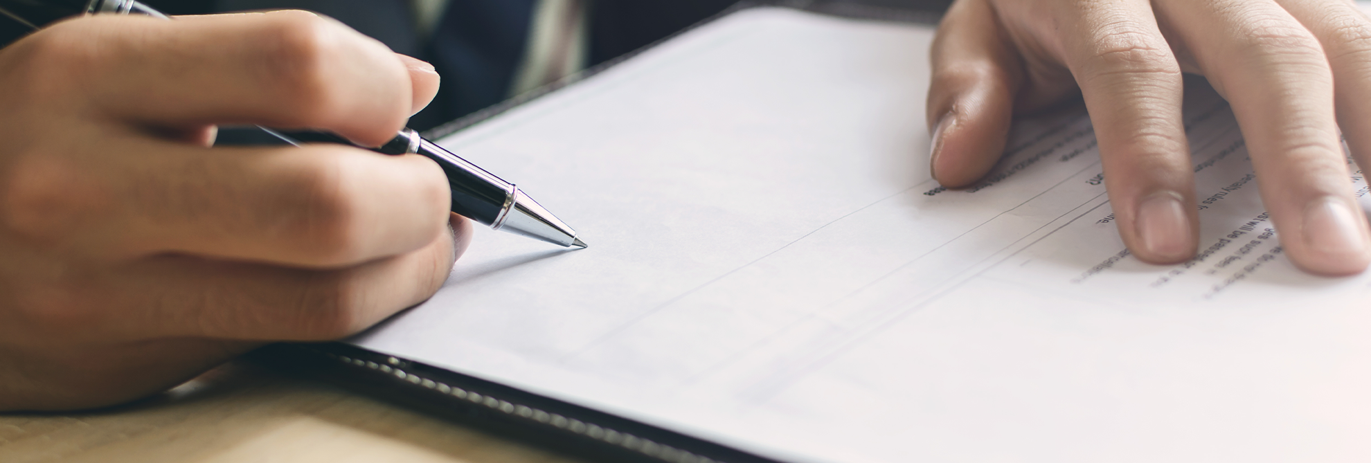 Mans hand signing on formal paperwork - Nassau County Appellate Attorney concept image