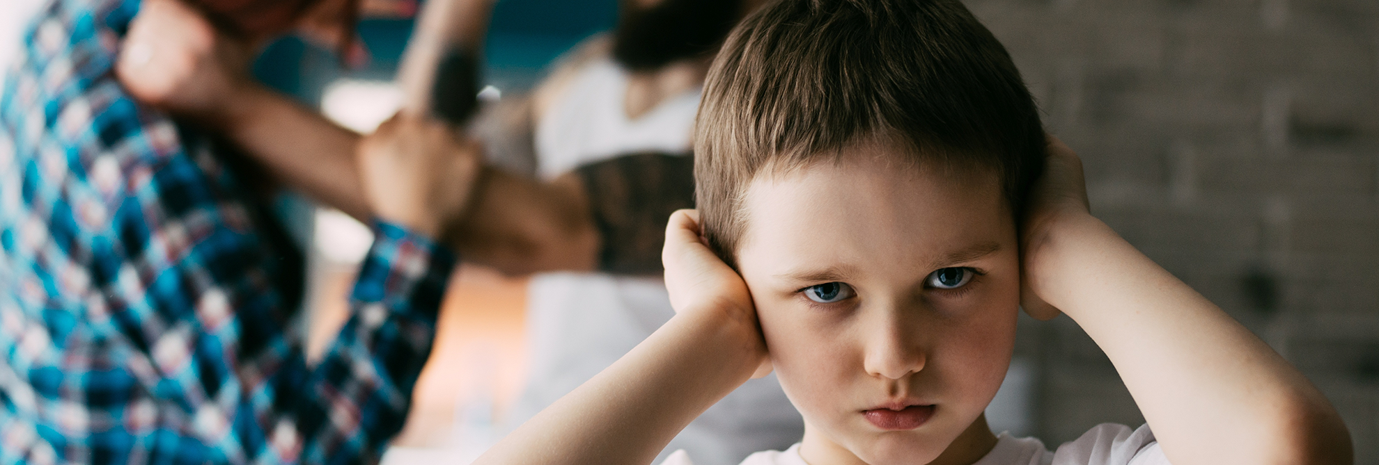 Sad child covering his ears with hands during parents quarrel