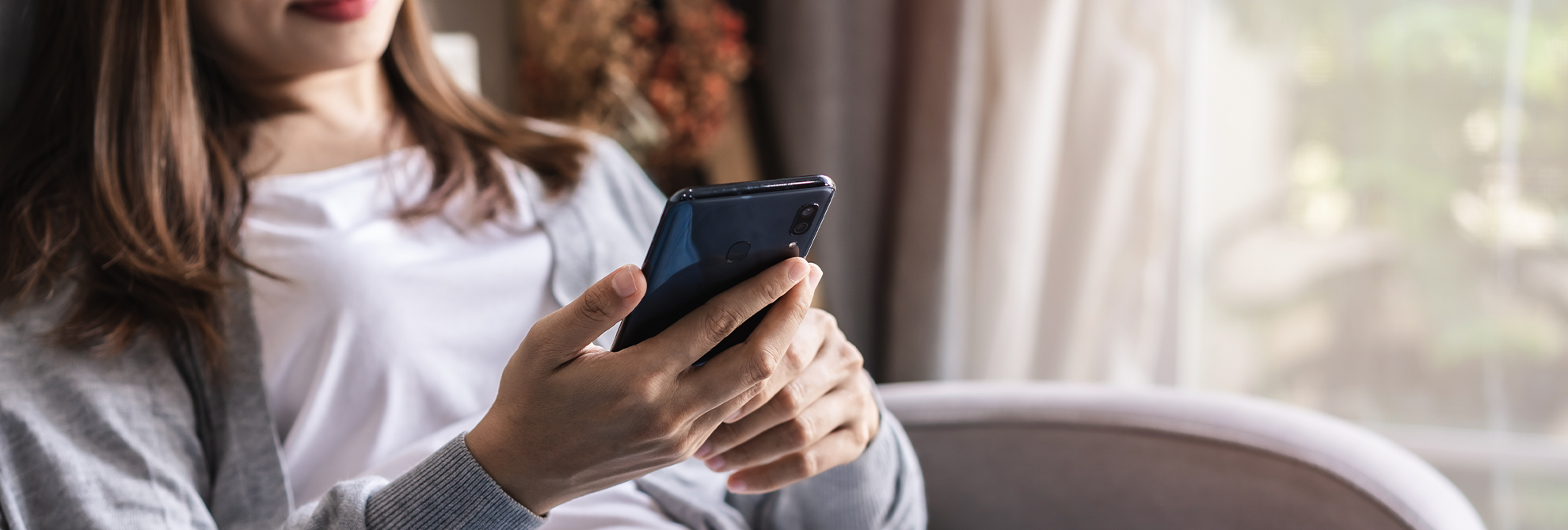 Young woman lying on sofa at living room and using cell phone at home