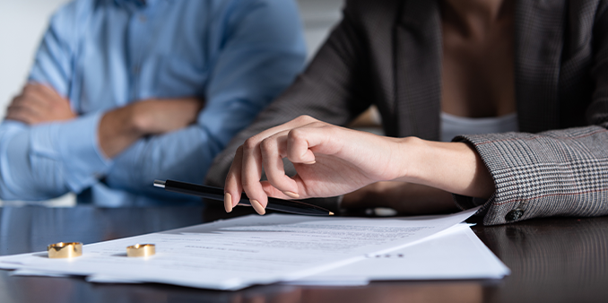 Man and woman at table with wedding bands on legal documents - Garden City Divorce Lawyer concept image