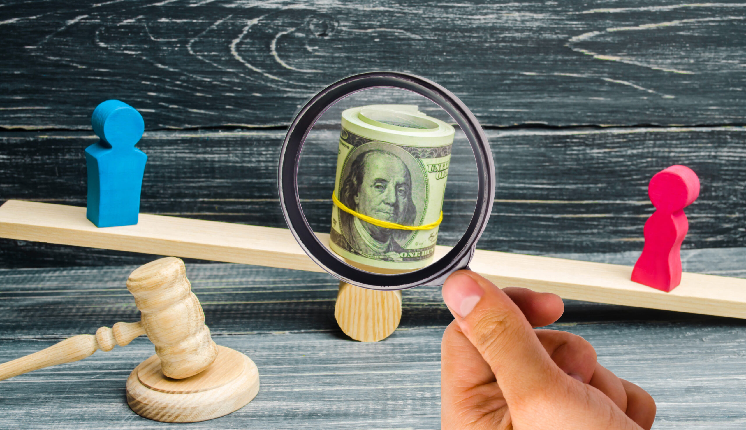 wooden figures on a balance beam with money magnifying glass and gavel