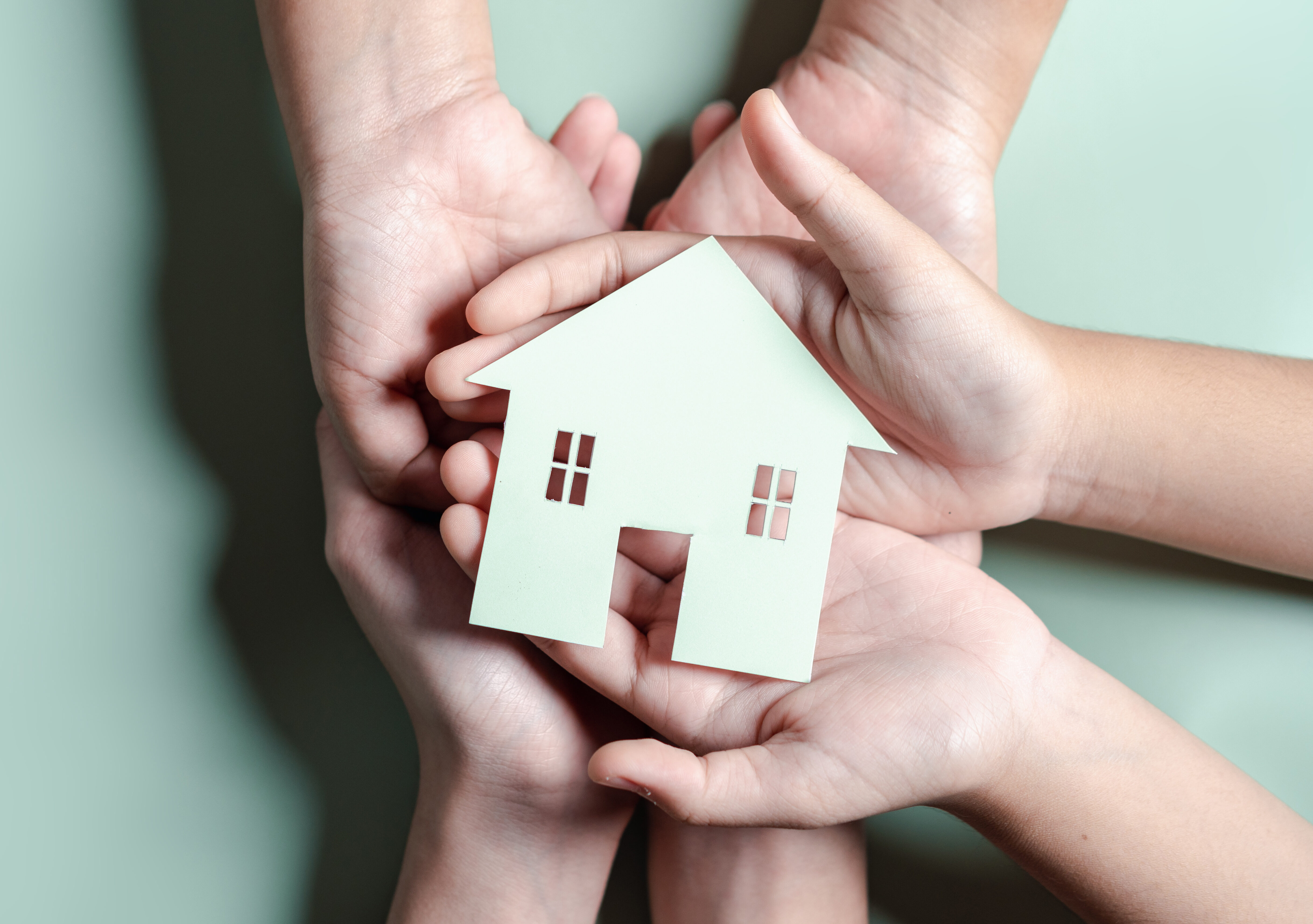 Hands holding wooden house, family home