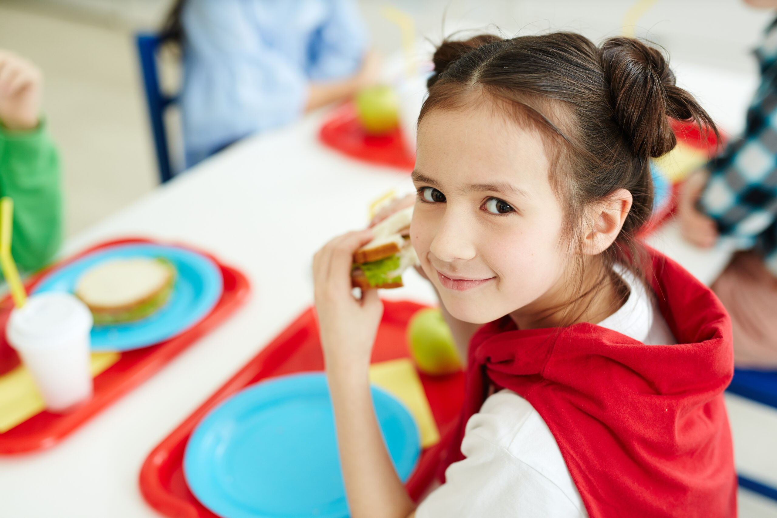 schoolgirl eating sandwich at lunch break after classes