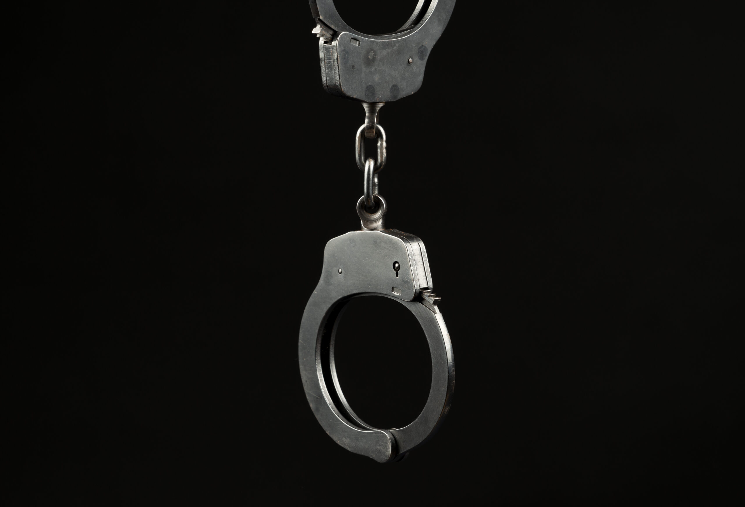 Locked police handcuffs on a black background with text / writing