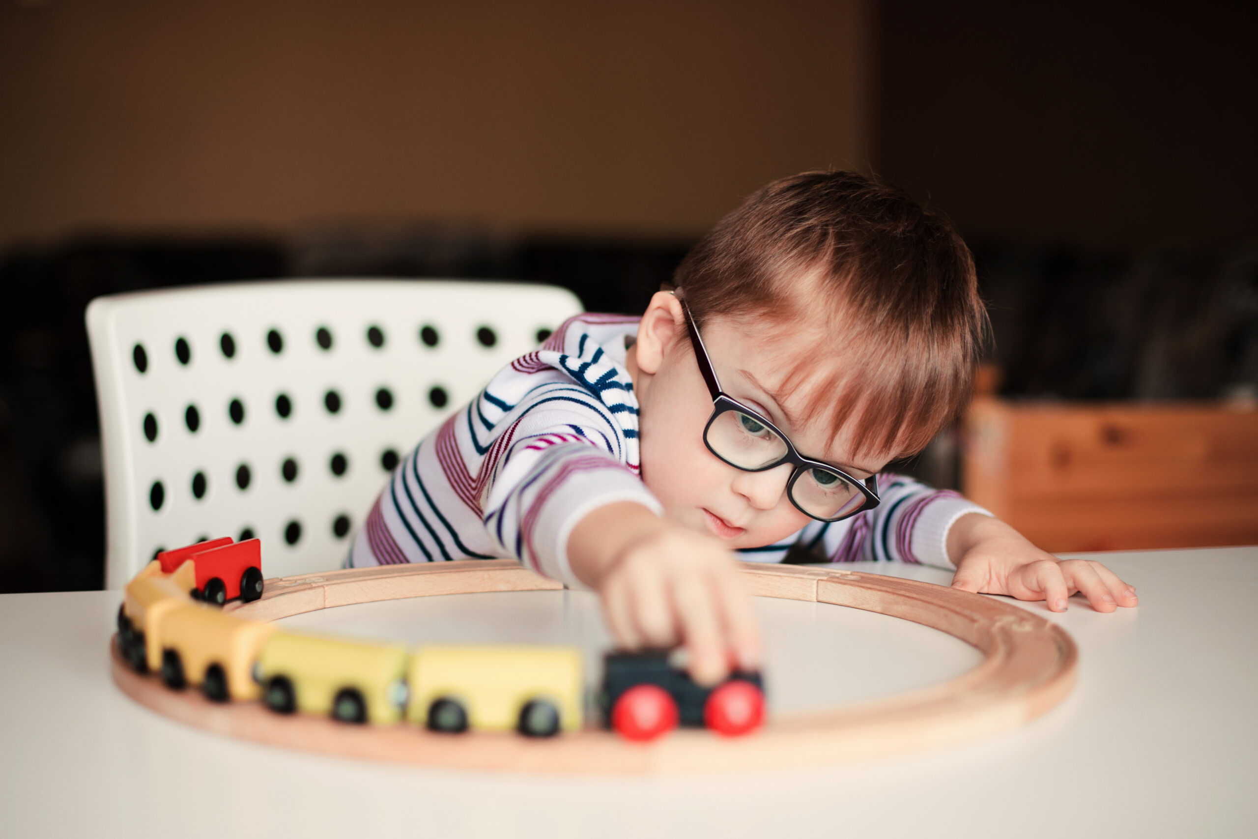 little boy with down syndrome playing with wooden train